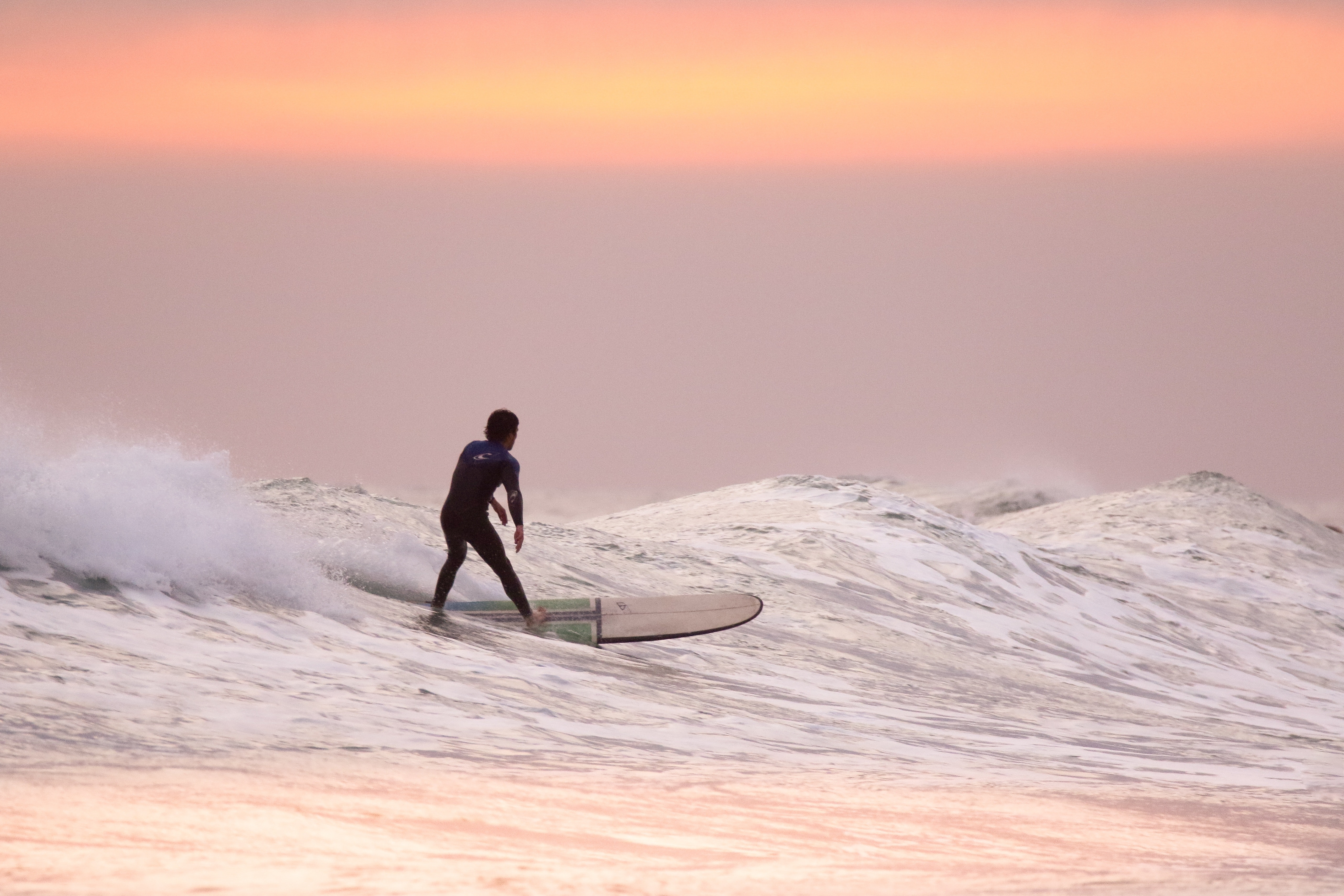 Surfers catching waves at sunset in Wilderness, Garden Route